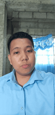 a man in a light blue shirt is looking at the camera