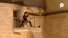 a man is playing a guitar and singing into a microphone on a balcony .