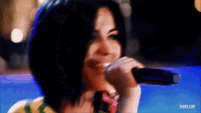 a close up of a woman singing into a microphone with rbd.gif below her