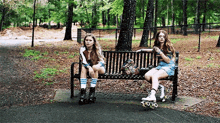 two girls are sitting on a bench in a park with roller skates .