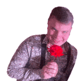 a man in a paisley shirt holds a red rose in his hand
