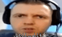 a man wearing headphones is making a funny face and has arabic writing on his face .