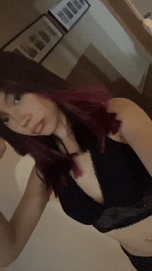 a woman with red hair is taking a selfie in a black bra