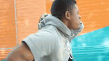 a man in a hoodie is pulling another man 's hoodie over his shoulder .