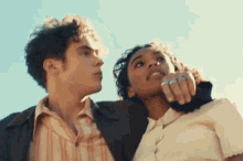 a man and a woman are looking up at the sky while standing next to each other .