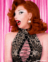 a woman with red hair is wearing a leopard print top and gold hoop earrings