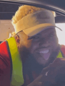 a man wearing a visor and safety vest is sticking his tongue out