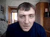 a man with a mustache is making a funny face while looking at the camera in a living room .