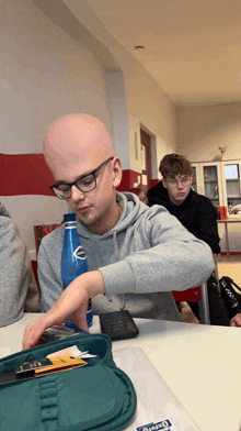 a bald man sits at a table with a pencil case that says oxford