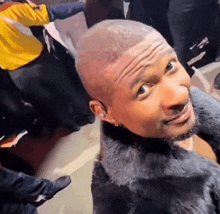 a man wearing a fur coat is standing in a crowd of people .