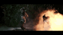 a woman is dancing in the rain in front of a fire and smoke .