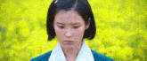 a woman with short hair is standing in front of a field of yellow flowers