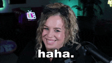 a woman in front of a microphone is smiling and the word haha is on her face