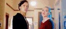 a man and a woman are looking at each other in a hallway .