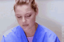 a close up of a woman wearing a blue scrub with her eyes closed