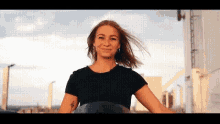 a woman in a black shirt is riding a motorcycle on a city street .