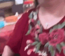 a woman in a red floral shirt is sitting at a table