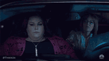 two women are sitting in the back seat of a car holding hands .