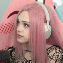 a girl with pink hair is wearing headphones and a black top