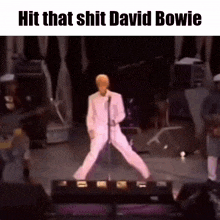 a man in a white suit is standing on one leg on a stage .