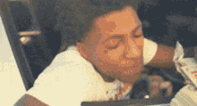 a young man in a white shirt is sitting in a car with his eyes closed .