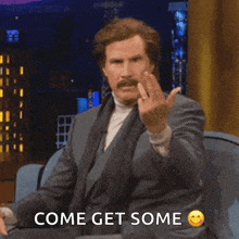 a man sitting on a couch giving the middle finger and the words come get some below him