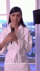 a woman in a white robe is standing in front of a window