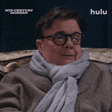 a man wearing glasses and a scarf is sitting in front of a screen that says hulu