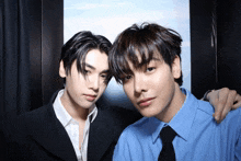 a man in a suit and a man in a blue shirt are posing for a picture
