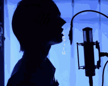 a silhouette of a person singing into a microphone with chinese writing behind them