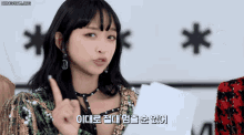 a woman in a green and gold outfit is holding a piece of paper and pointing up with a foreign language behind her