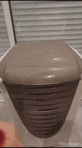 a dirty laundry basket is sitting on a tiled floor in front of a window