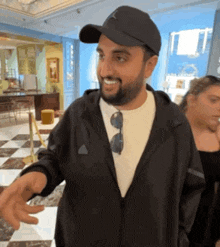 a man with a beard wearing a black jacket and a black hat