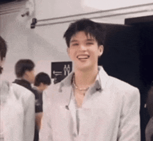 a young man is smiling in a room with other people .
