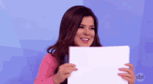 a woman is holding a piece of paper with sbt written on the bottom