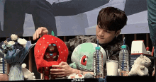 a man is sitting at a table with a stuffed animal and a strawberry hat .
