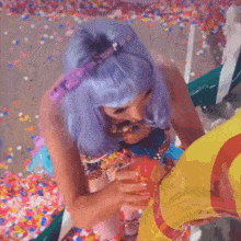 a woman in a purple wig is standing in a pile of confetti ..