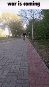 a person riding a bike down a brick sidewalk with the words war is coming on the top