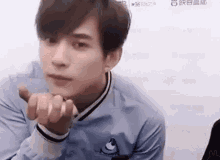 a young man is making a heart shape with his hands .