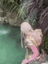 a woman in a feathered costume is standing in a body of water .