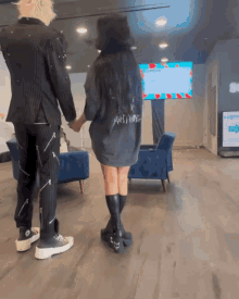 a man and a woman are holding hands in front of a screen that says ' covid 19 ' on it