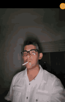 a man with glasses is smoking a cigarette in a dark room
