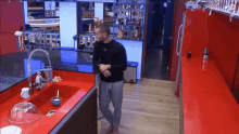 a man is standing in a kitchen with a red counter top and a sink