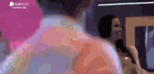 a man and a woman are dancing in a room with a playplus logo in the background .