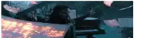 a man is playing a piano in a dark room with flames behind him .