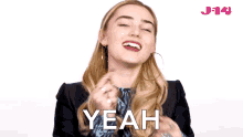 a woman is smiling and says yeah in front of a j14 logo