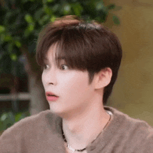 a close up of a young man wearing a sweater and a necklace .