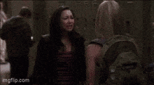 two women are standing next to each other holding hands in a dark room .