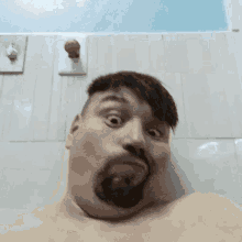 a man with a beard is making a funny face in a bathroom