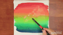 a person is painting a rainbow on a canvas with the words made in animotica visible